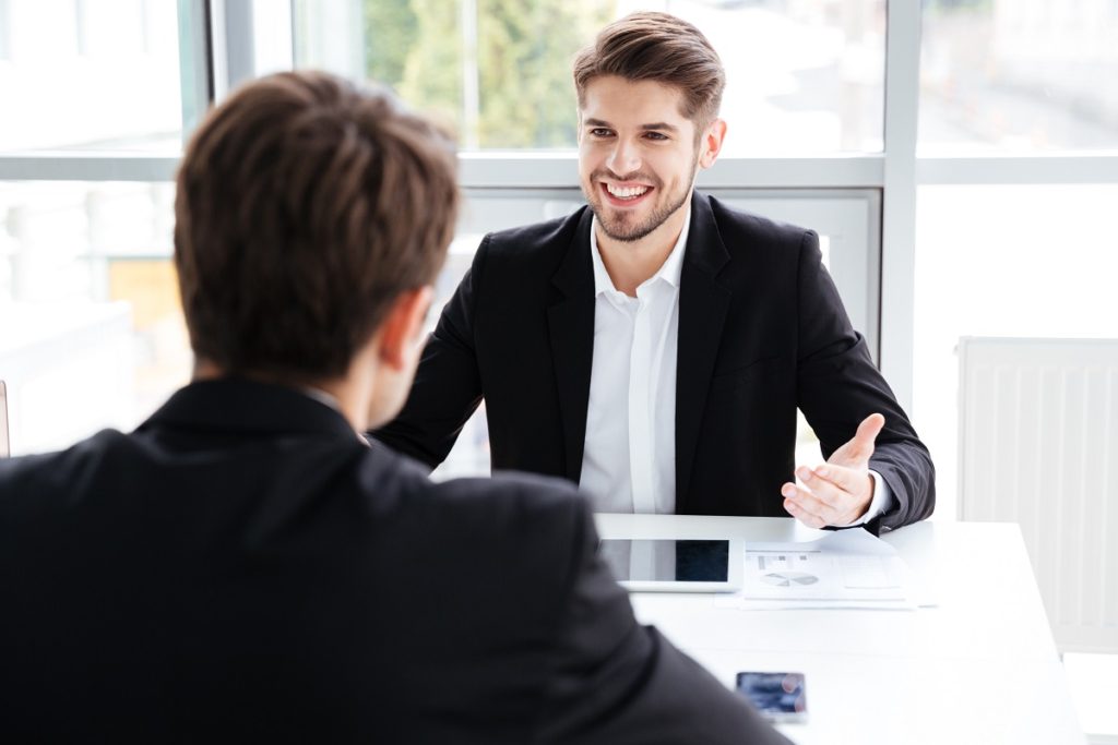 Two cheerful businessmen using tablet and working on business meeting